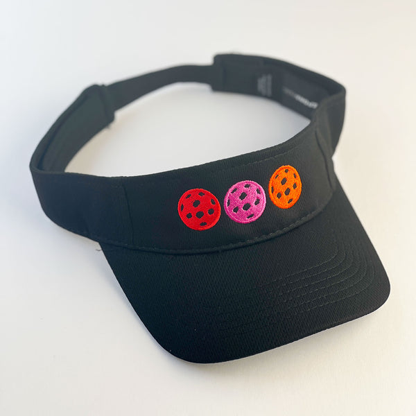 black visor with embroidered pickleballs in hot pink, red, and orange